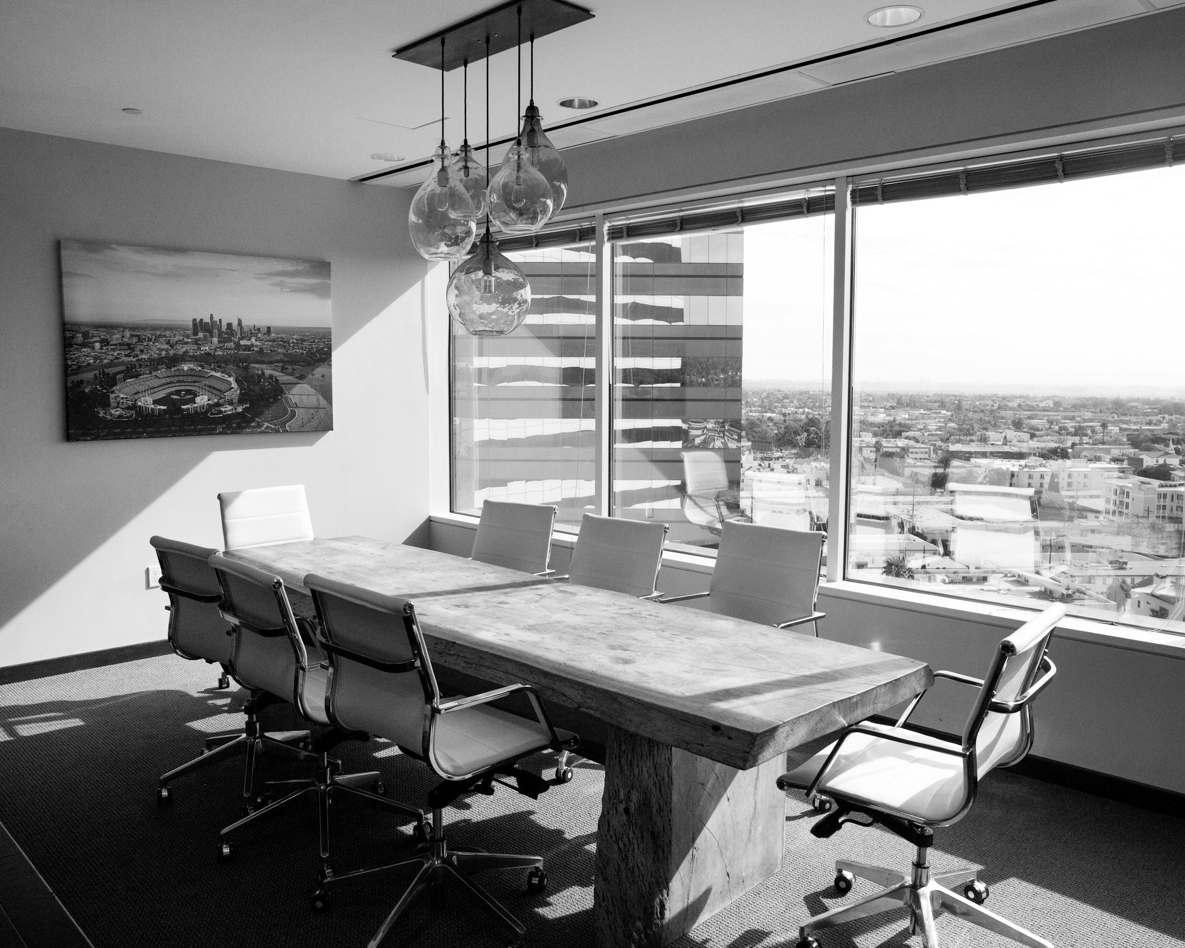 A boardroom table beside windows overlooking the city
